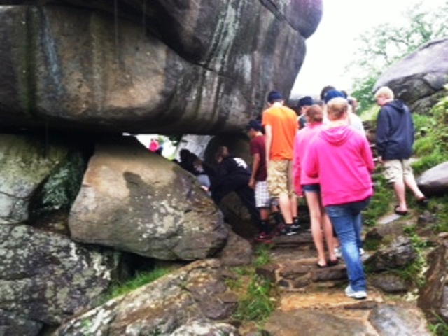 students walking under a large boulder